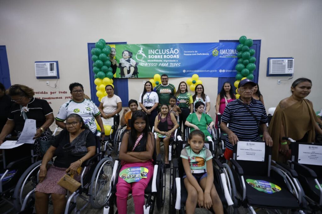Usuários de cadeiras de rodas e seus familiares sorrindo para a foto enquanto recebem suas cadeiras de rodas