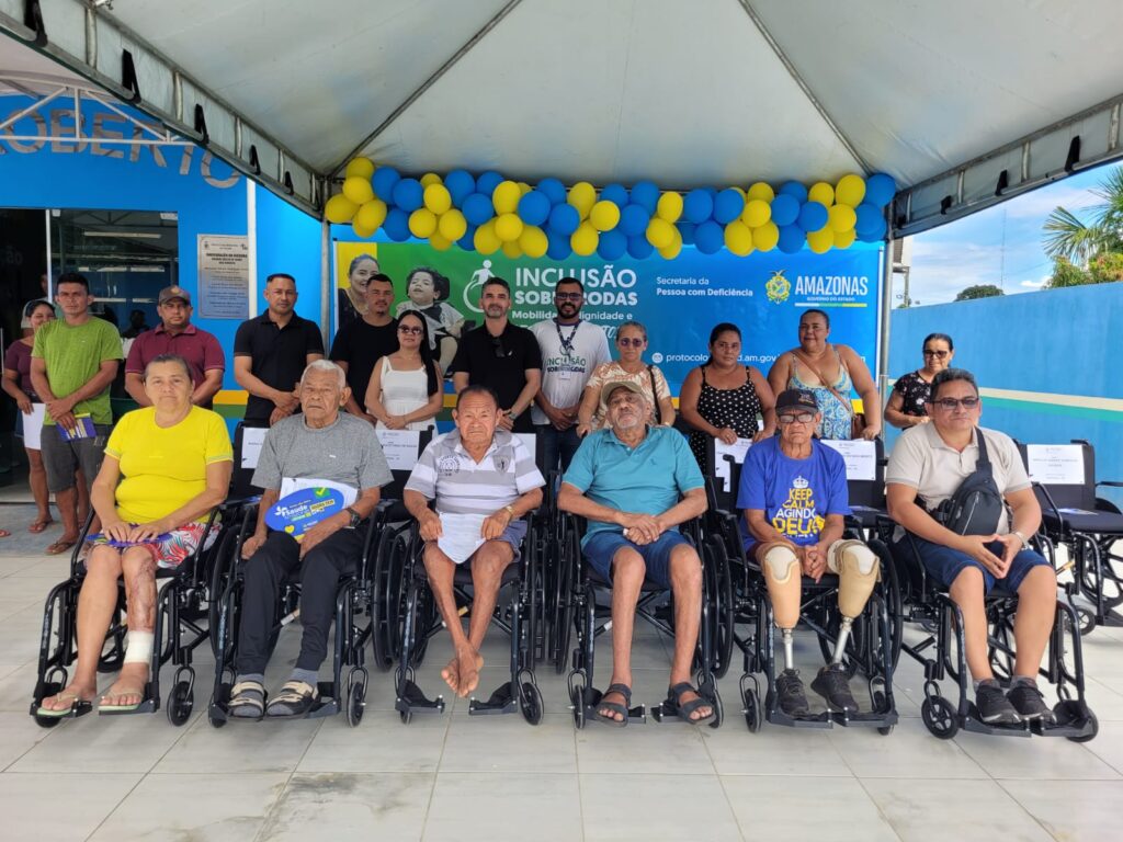 Imagem do secretário adjunto da SEPcD, Adriano Reis, com os beneficiados na entrega de cadeiras de rodas