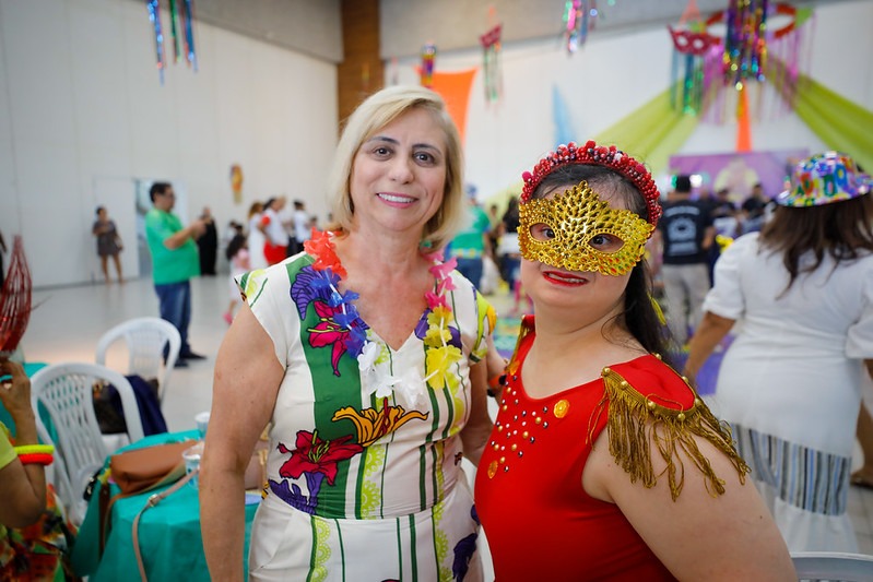 Imagem da mãe e de sua filhas com adereços de carnaval sorrindo para a foto