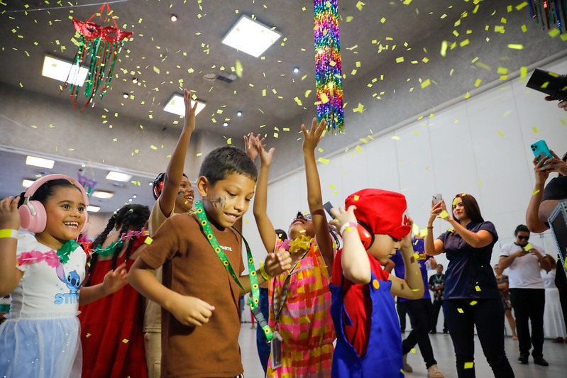 imagem das crianças brincando fantasiadas e com confete ao redor 