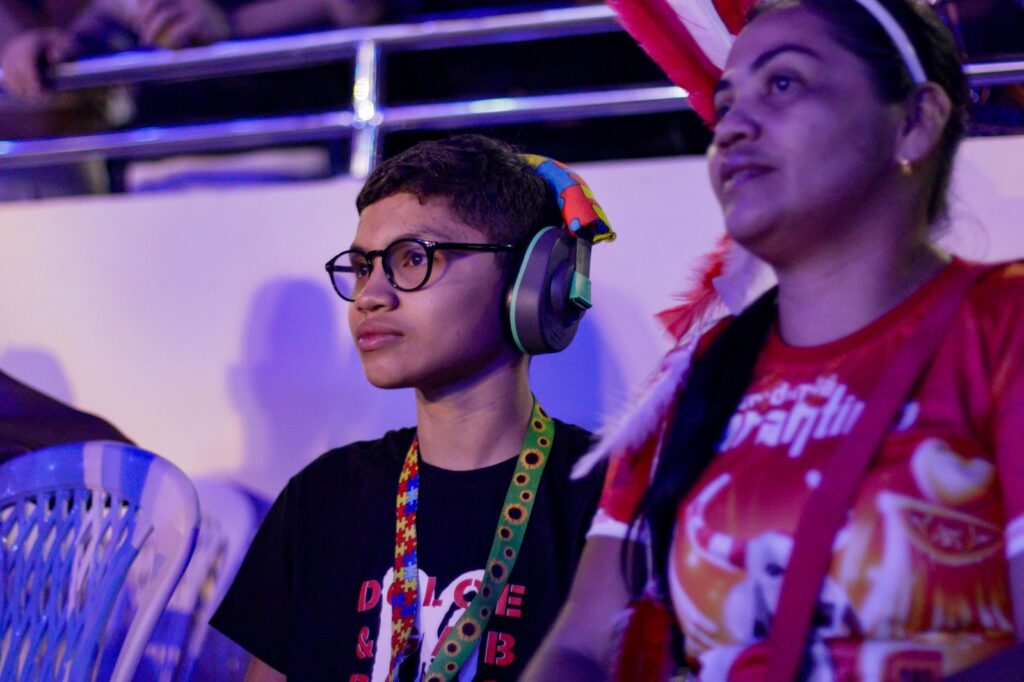 imagem de um menino com abafador e o cordão de girassóis ao lado de sua mãe