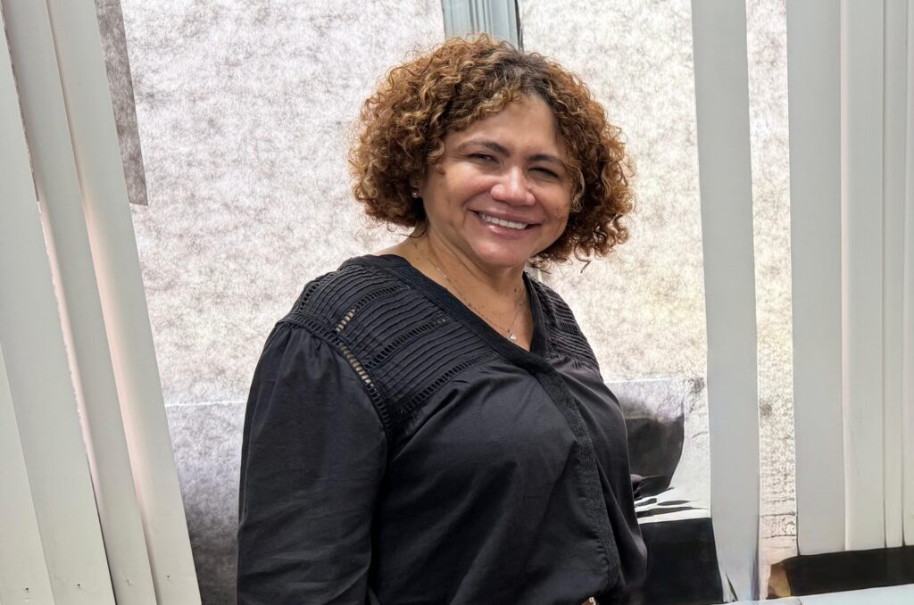 secretária selma sorrindo para a foto e vestindo uma blusa preta 