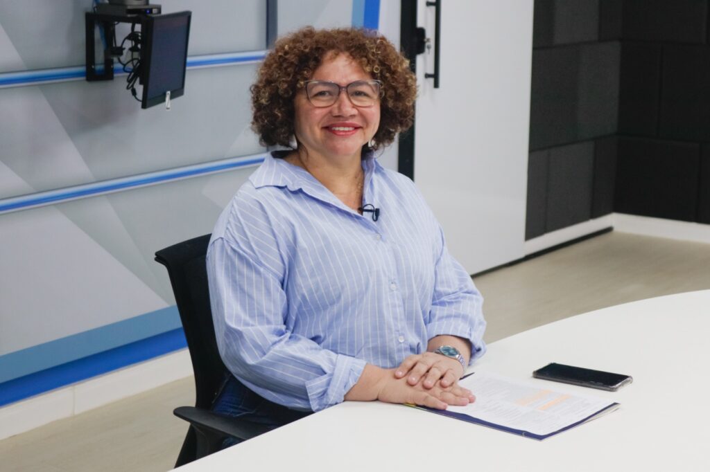 imagem da secretária Selma sentada em uma cadeira e sorrindo para a foto